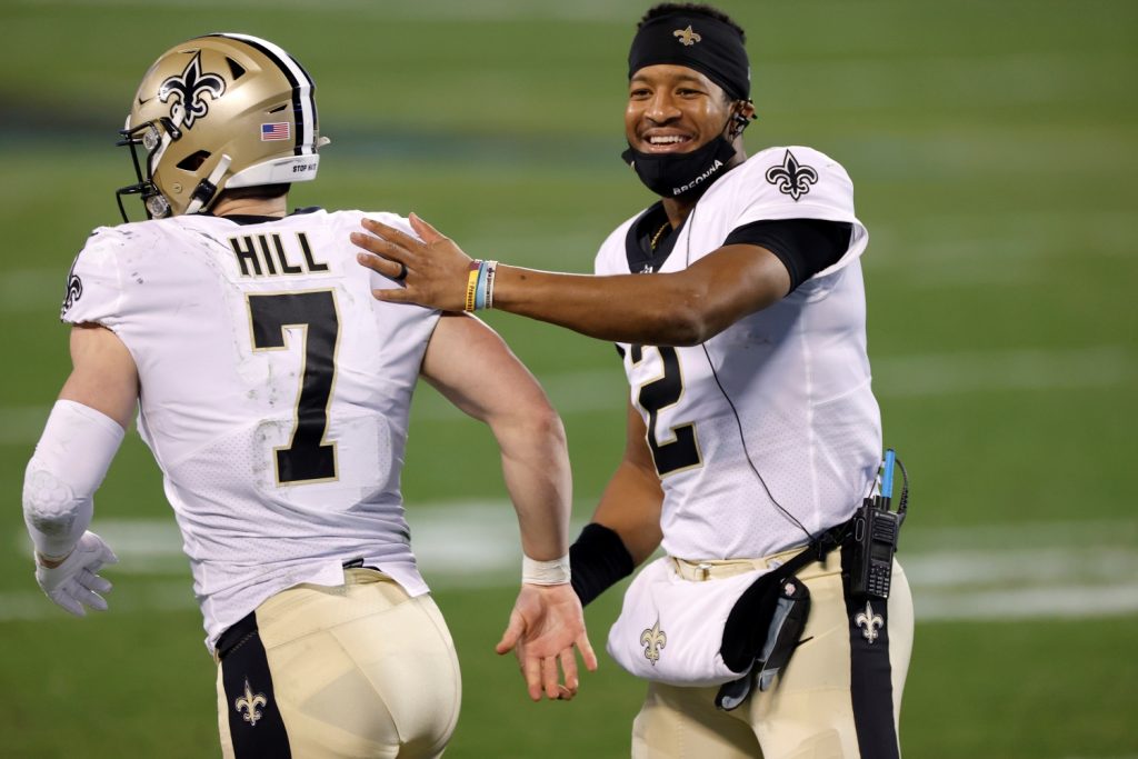 New Orleans Saints quarterback Jameis Winston taps teammate Taysom Hill on the back as he jogs onto the field.