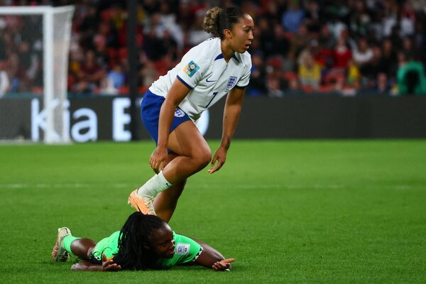 England’s Lauren James is stepping on the back of Michelle Alozie, who is lying on the grass.