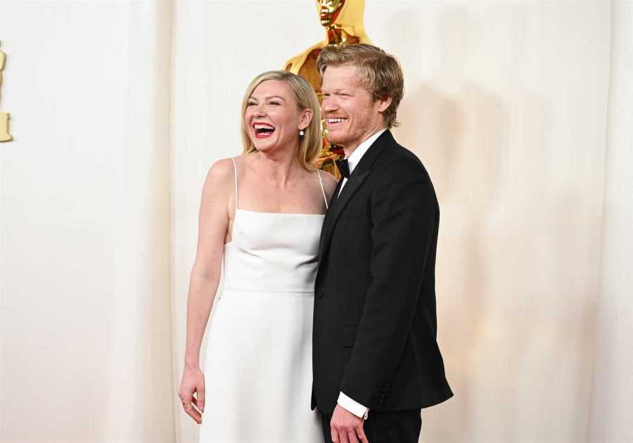 Kirsten Dunst bumps into a statue as she walks the red carpet at the Oscars with husband Jesse Plemons